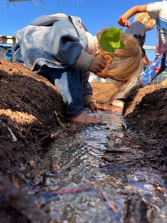 Child exploring mud and water
